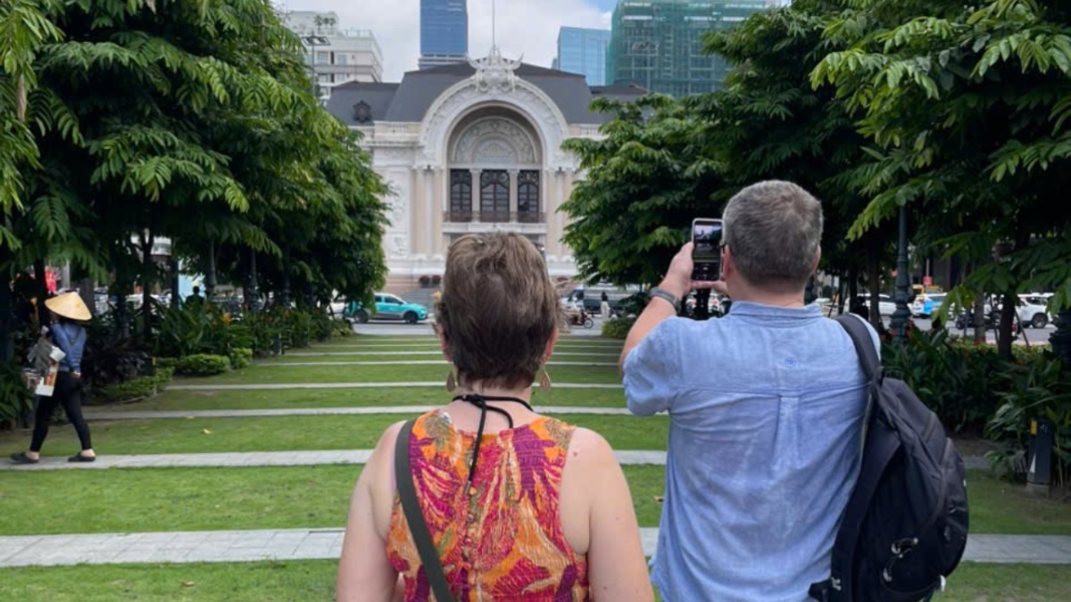 Western travelers photographing the Saigon Opera House during a local walking tour in Ho Chi Minh City